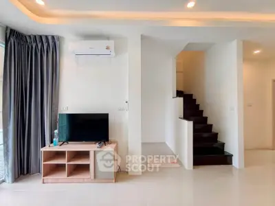 Modern living room with sleek staircase and wall-mounted air conditioner