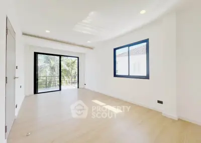 Spacious bright living room with large windows and balcony access in modern home.