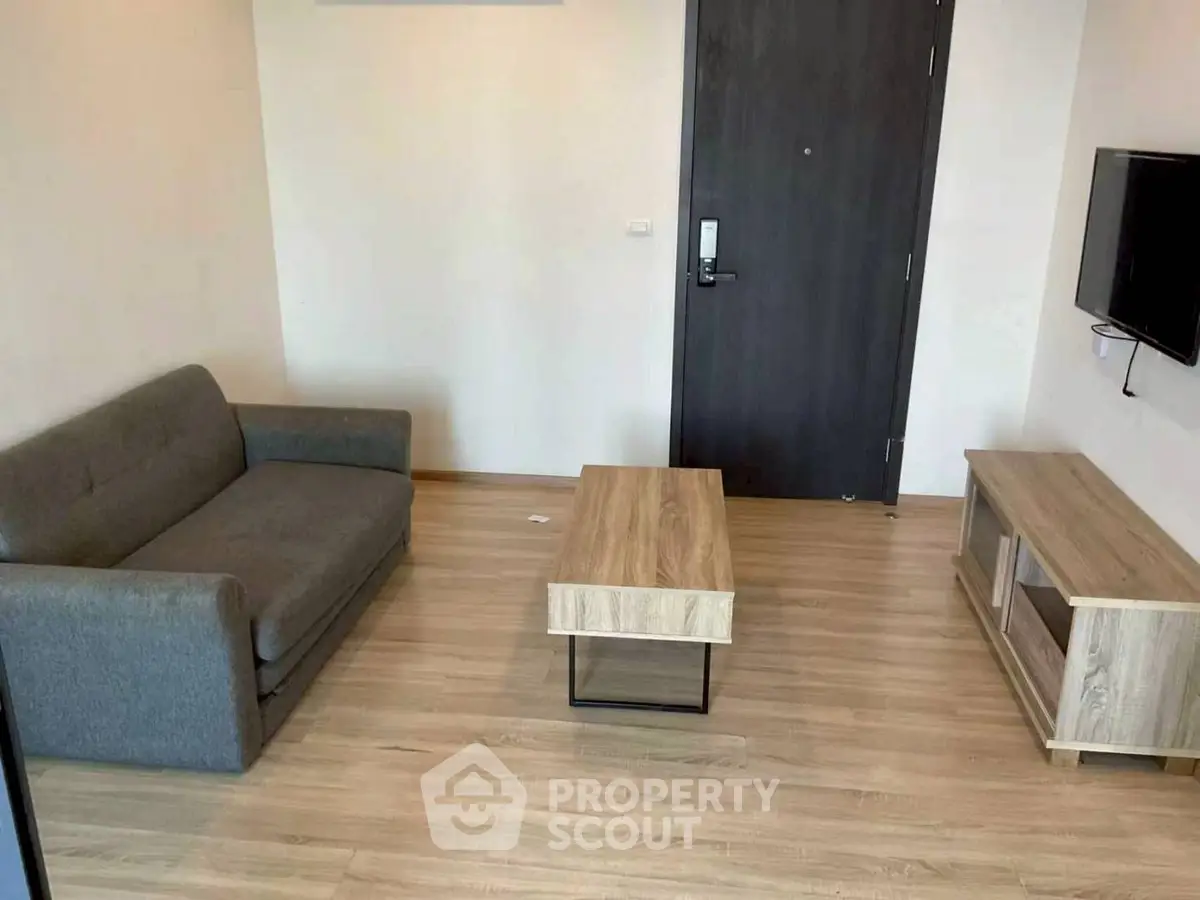 Modern living room with minimalist furniture and wooden flooring, featuring a cozy sofa and sleek TV stand.