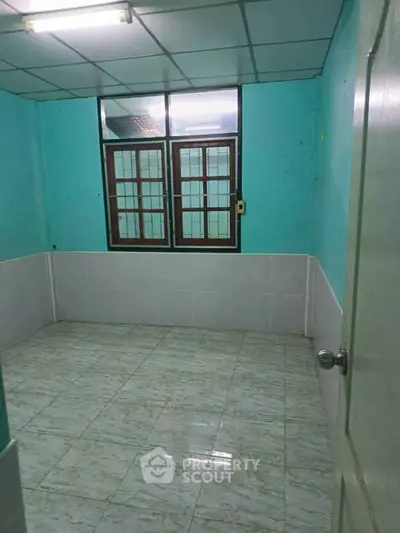 Spacious empty room with tiled floor and large window, ideal for customization.