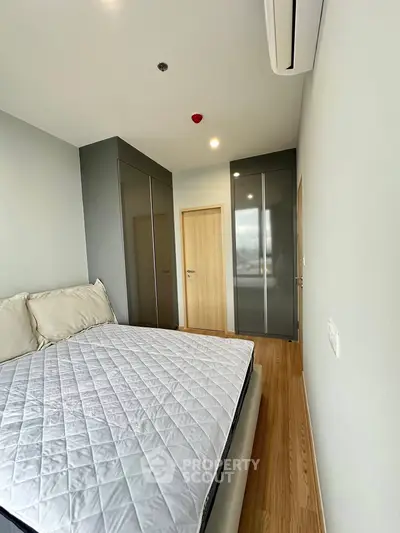 Modern bedroom with sleek wardrobes and wooden flooring, featuring a comfortable bed and minimalist design.