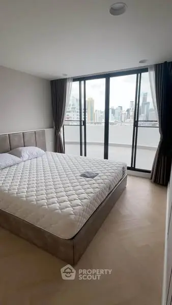 Modern bedroom with city view and large windows in a high-rise apartment.