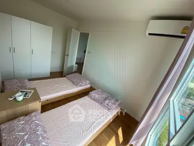 Bright bedroom with twin beds, air conditioning, and a scenic window view.