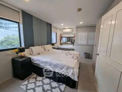 Modern bedroom with stylish decor and ample natural light in urban apartment.