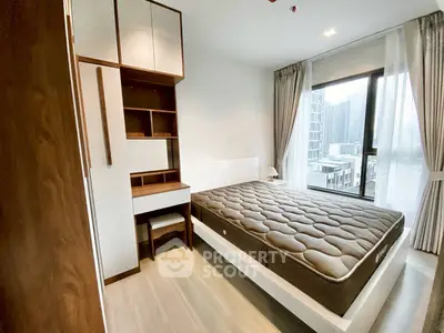 Modern bedroom with large window and built-in storage in urban apartment