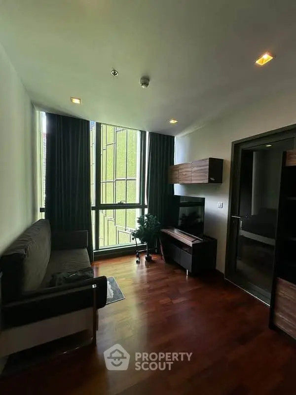 Modern living room with hardwood floors, large windows, and stylish furniture in a high-rise apartment.