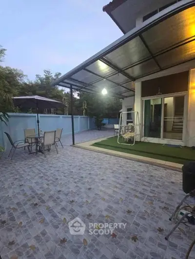 Spacious outdoor patio with modern furniture and swing in a serene residential setting.