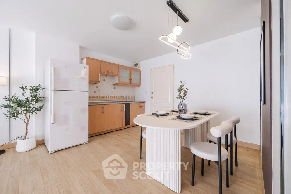 Modern kitchen with dining area, featuring sleek wooden cabinets and contemporary lighting.