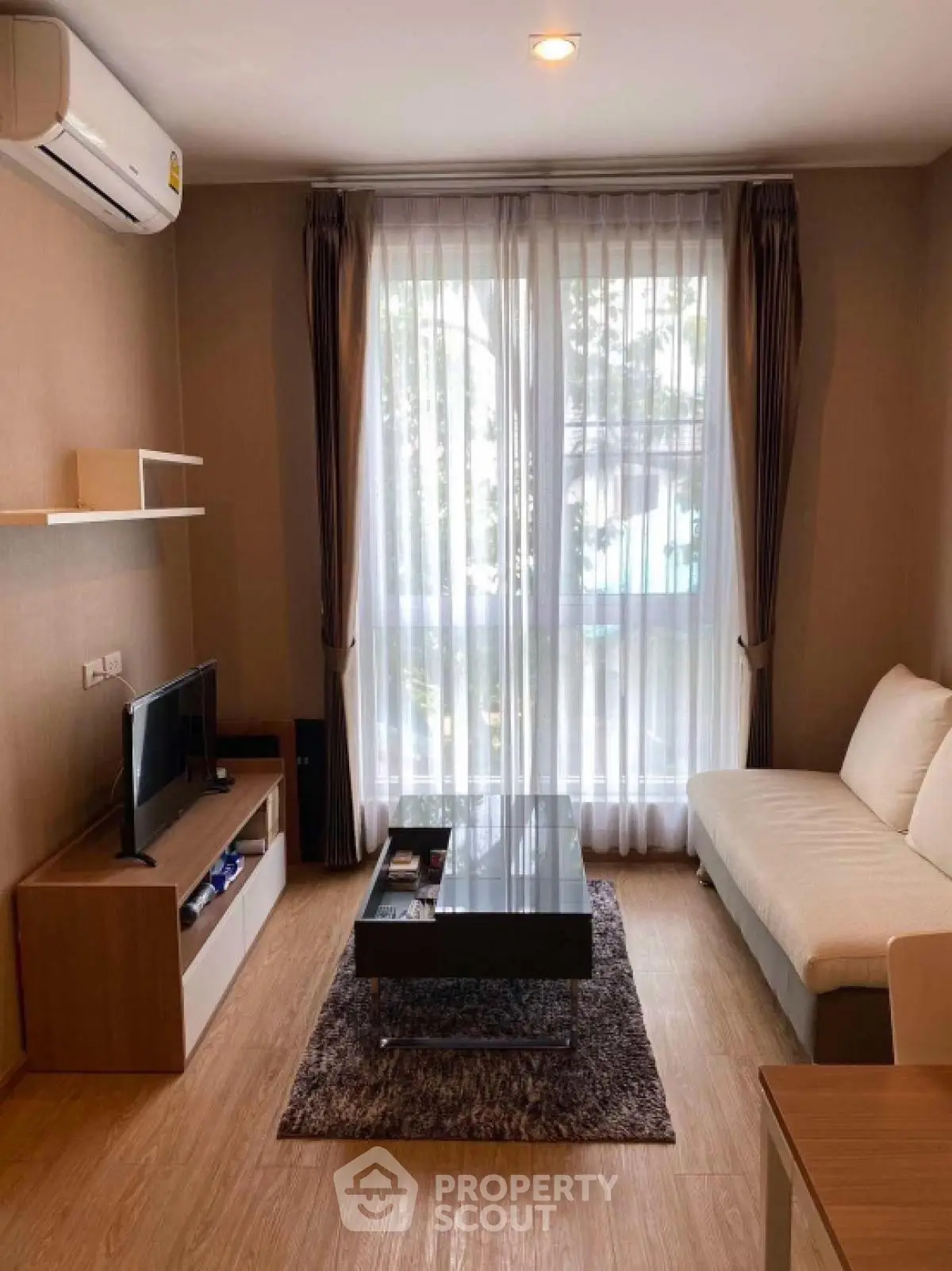 Cozy living room with modern decor, featuring a comfortable sofa and large window for natural light.