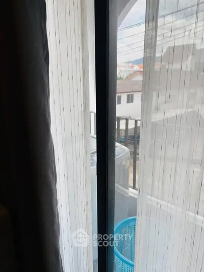 Cozy balcony view through sheer curtains in a modern apartment setting.