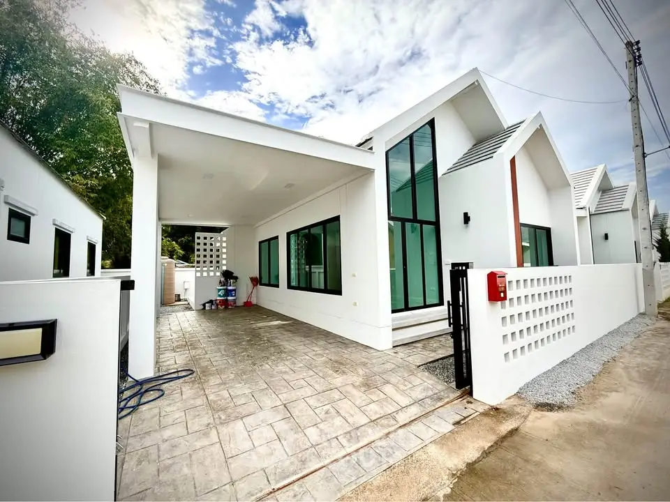 Modern white house with sleek design and spacious driveway under a clear blue sky.