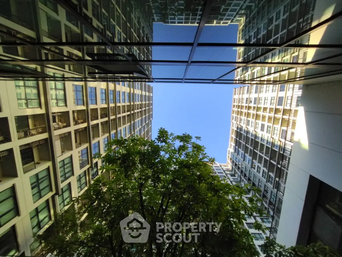Stunning view of modern high-rise buildings with lush greenery and clear blue sky.