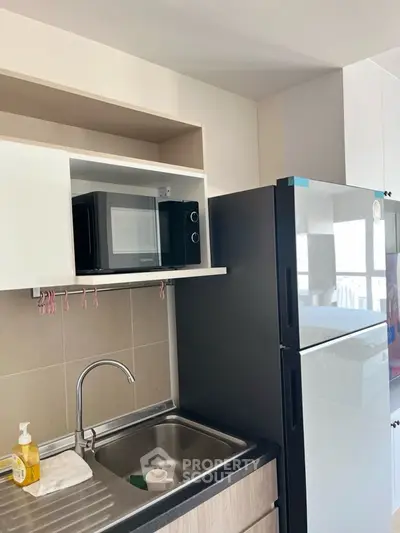 Modern kitchen with microwave and fridge in compact layout