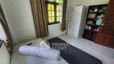 Cozy bedroom with natural light, featuring a bed, wardrobe, and bookshelf, ideal for a comfortable living space.