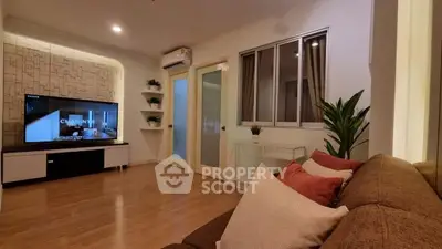 Modern living room with stylish decor and large TV, featuring cozy seating and elegant lighting.