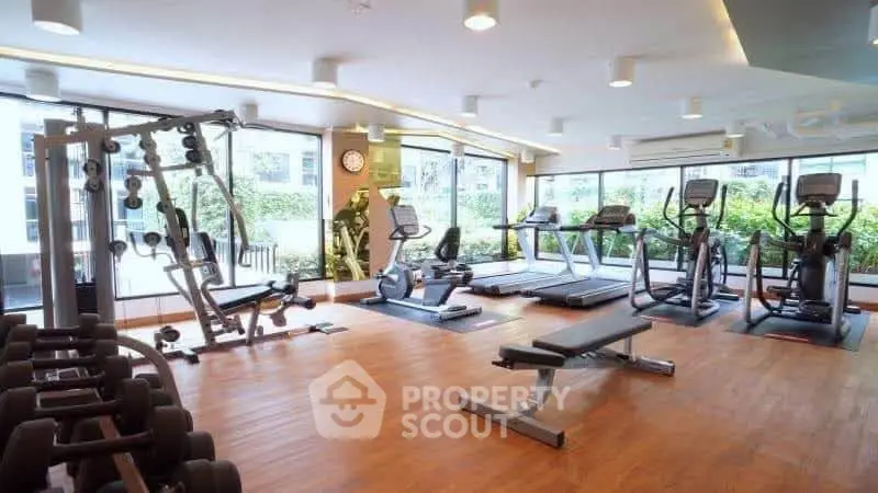 Spacious modern gym with state-of-the-art equipment and large windows for natural light.