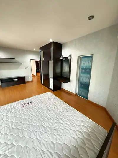Spacious bedroom with modern design and wooden flooring, featuring built-in wardrobe and ample natural light.