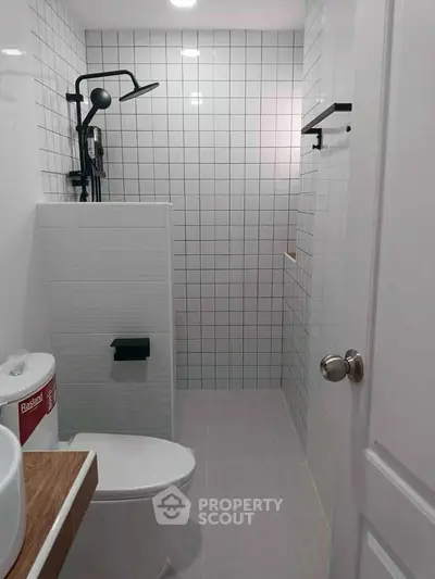 Modern bathroom with sleek fixtures and minimalist design, featuring a walk-in shower and contemporary tiles.