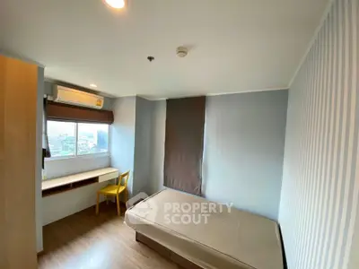 Cozy bedroom with large window and modern furnishings in a stylish apartment.