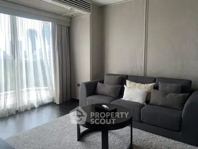 Modern living room with sleek gray sofa and city view through large windows.
