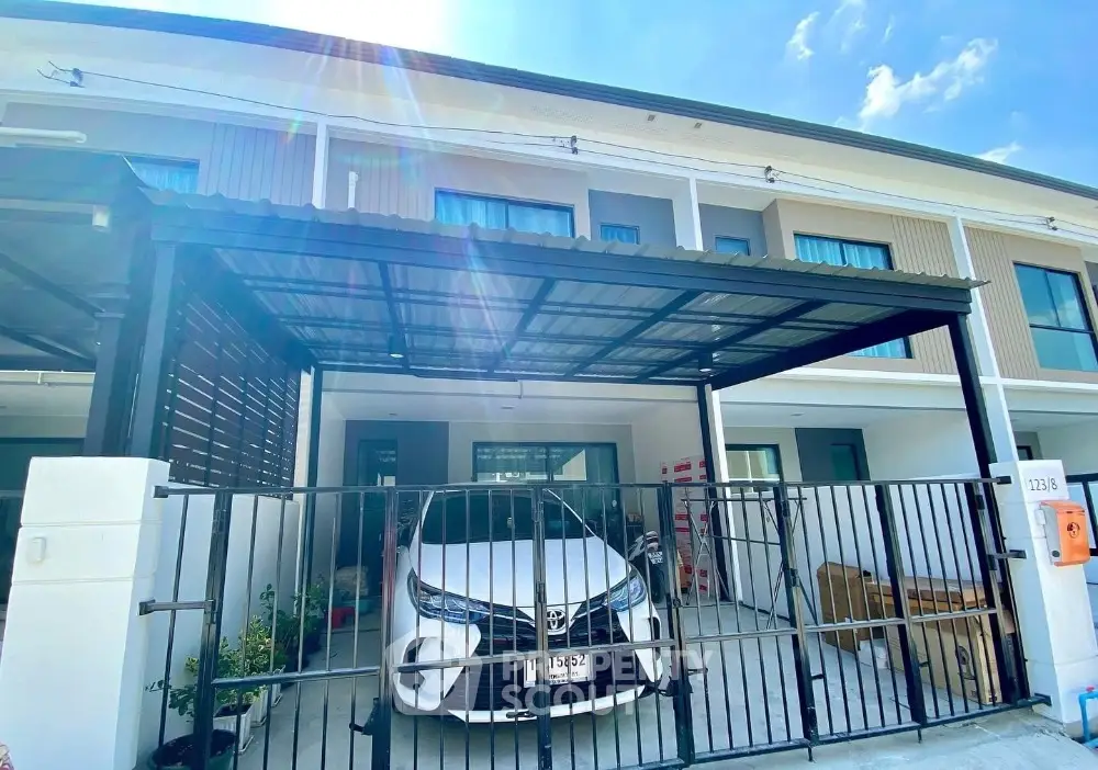 Modern townhouse with covered parking and sleek facade under a bright blue sky.