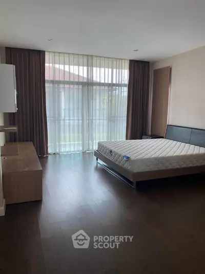 Spacious bedroom with large windows and modern furnishings, perfect for natural light lovers.