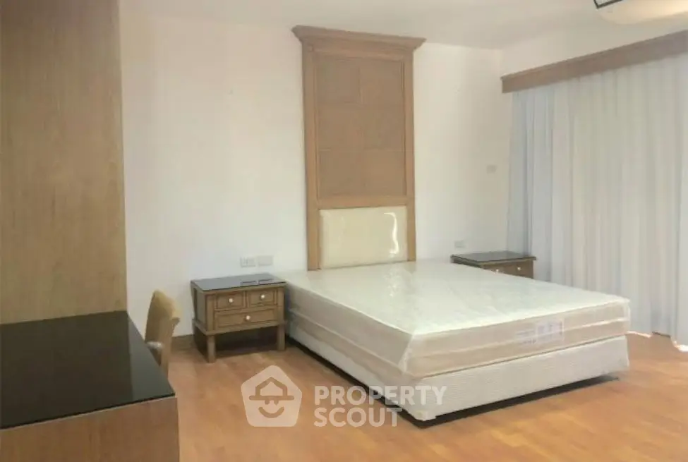 Spacious bedroom with modern furniture and natural light, perfect for comfortable living.