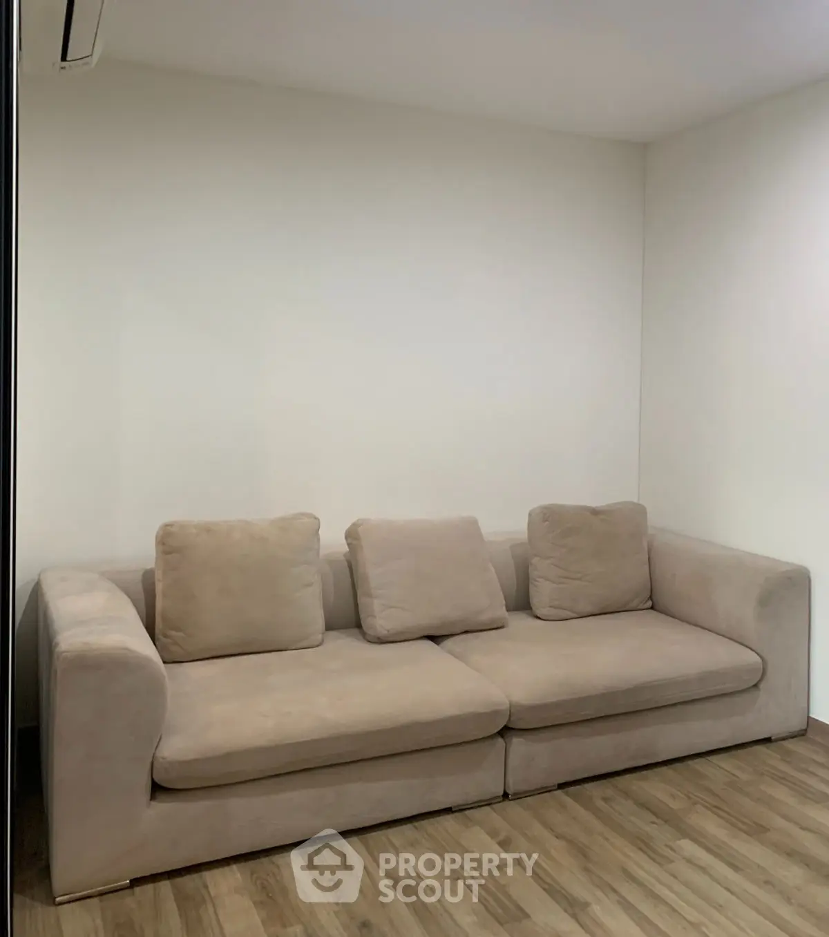 Cozy beige sofa in a minimalist living room with wooden flooring.