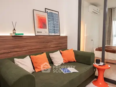 Modern living room with stylish decor and cozy green sofa, featuring a glimpse into a chic bedroom.