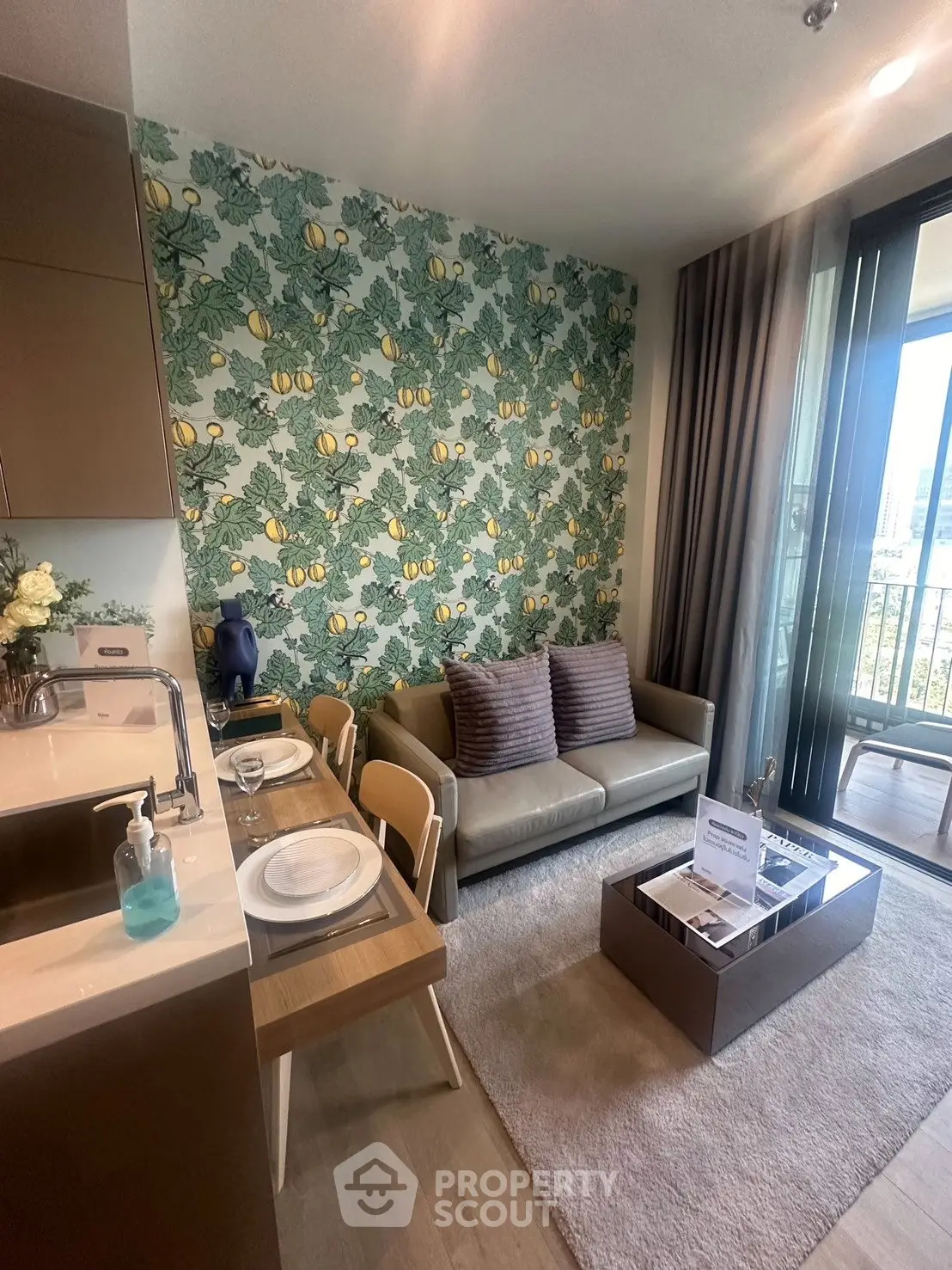 Chic living room with vibrant lemon wallpaper and cozy seating area, adjacent to a modern kitchen.