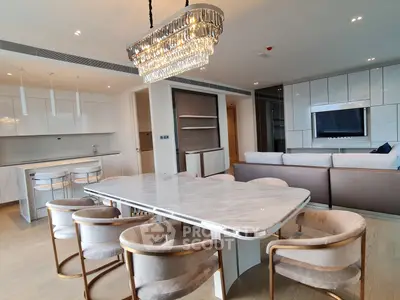 Luxurious open-plan living and dining area with elegant chandelier and modern furnishings.
