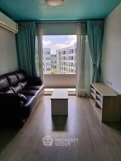 Modern living room with black leather sofa and large window view in a stylish apartment.