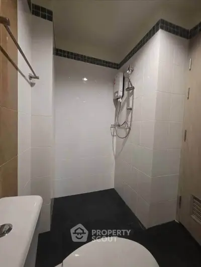 Modern bathroom with sleek white tiles and compact shower area, perfect for urban living.