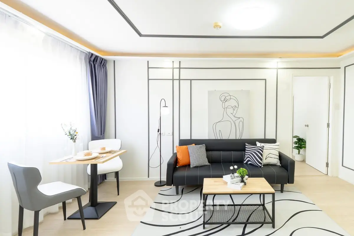 Modern living room with stylish decor, black sofa, and artistic wall design in a bright apartment.