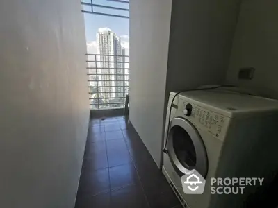 Compact laundry area with washing machine and city view from balcony.