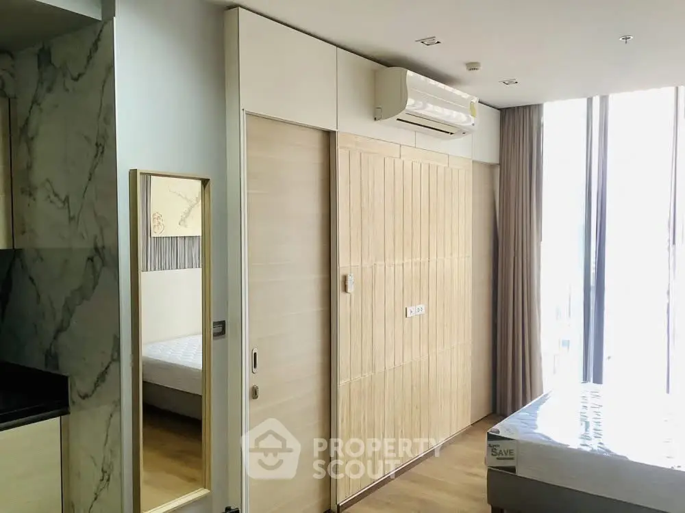 Modern bedroom with sliding wooden doors and air conditioning in a bright apartment.