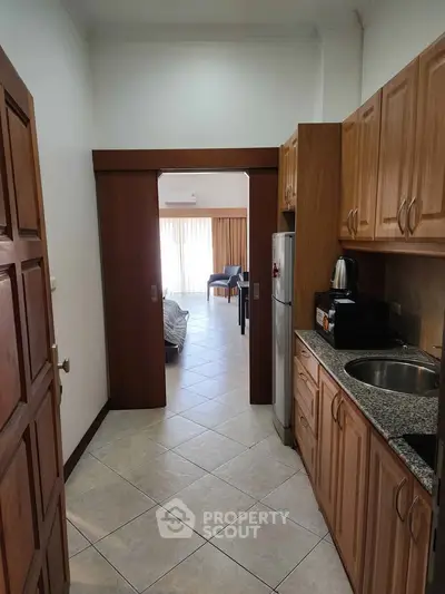 Spacious kitchen with wooden cabinets leading to a bright living area