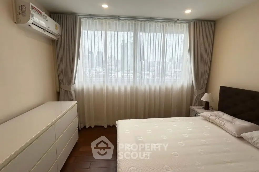 Cozy bedroom with large window and elegant curtains in modern apartment