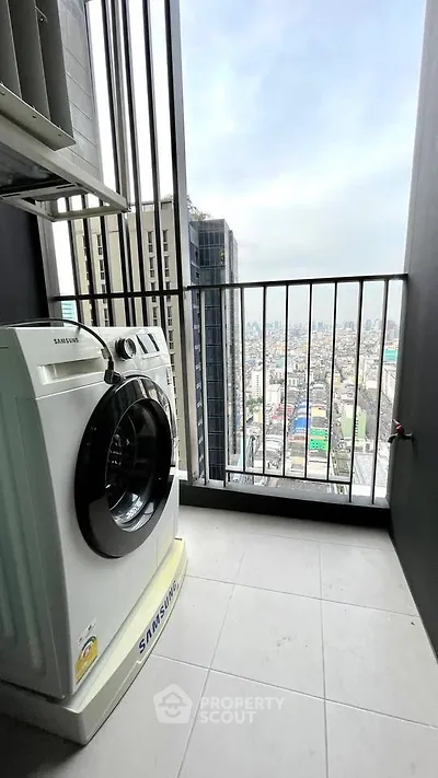 High-rise apartment balcony with city view and washing machine.