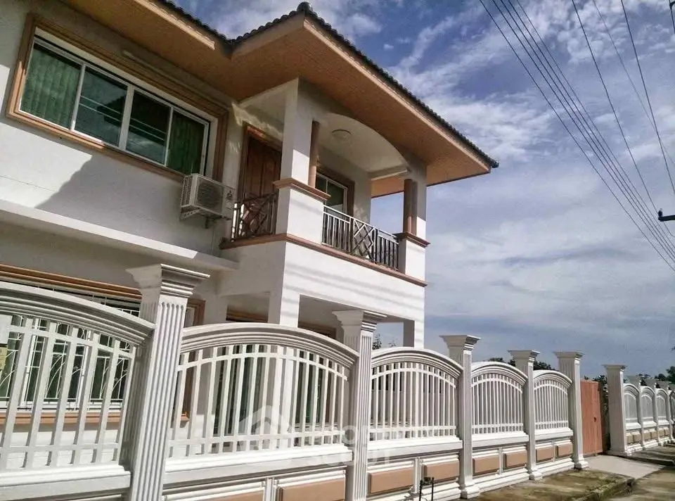 Elegant two-story house with balcony and decorative fence under a clear sky.