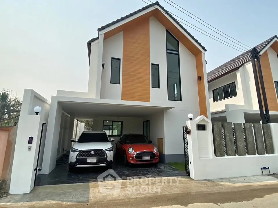 Modern two-story house with spacious driveway and two cars parked, showcasing contemporary architecture.