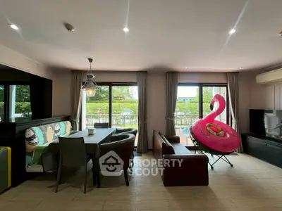 Spacious living room with dining area and large windows opening to a garden view.