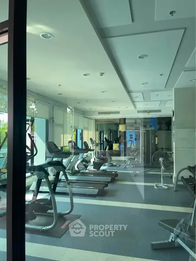 Modern gym with state-of-the-art equipment and large windows for natural light.