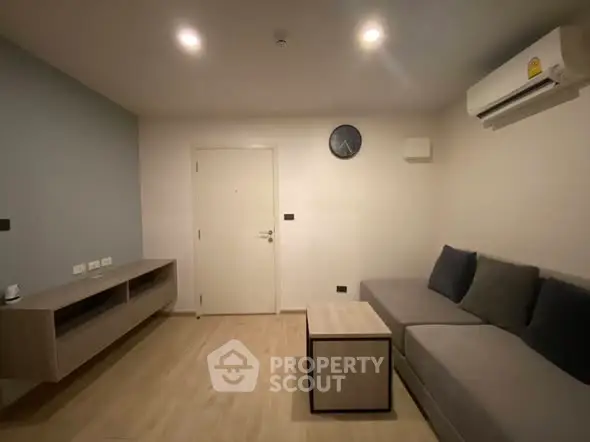 Modern living room with sleek furniture and minimalist design, featuring a comfortable sofa and wall-mounted air conditioner.