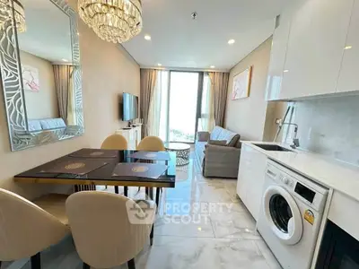 Modern living room with dining area and washing machine, featuring elegant decor and natural light.