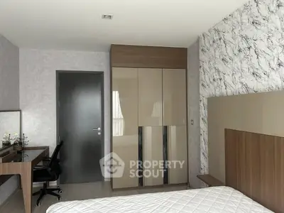 Modern bedroom with stylish wardrobe and workspace, featuring elegant decor and natural light.