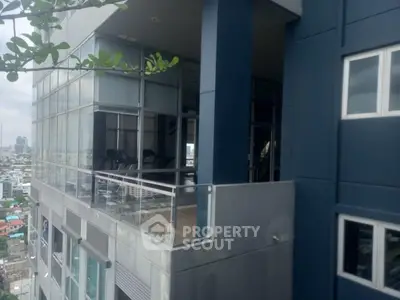 Modern high-rise building with glass facade and balcony offering city views.