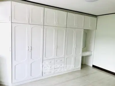 Spacious bedroom with built-in white wardrobes and vanity mirror