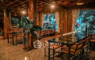 Charming rustic dining area with wooden beams and large windows overlooking lush greenery.