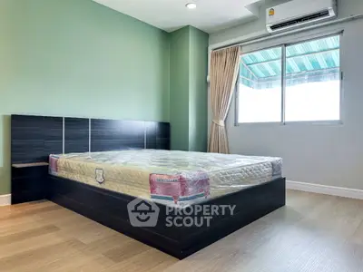 Modern bedroom with large window and stylish bed frame in a cozy apartment.